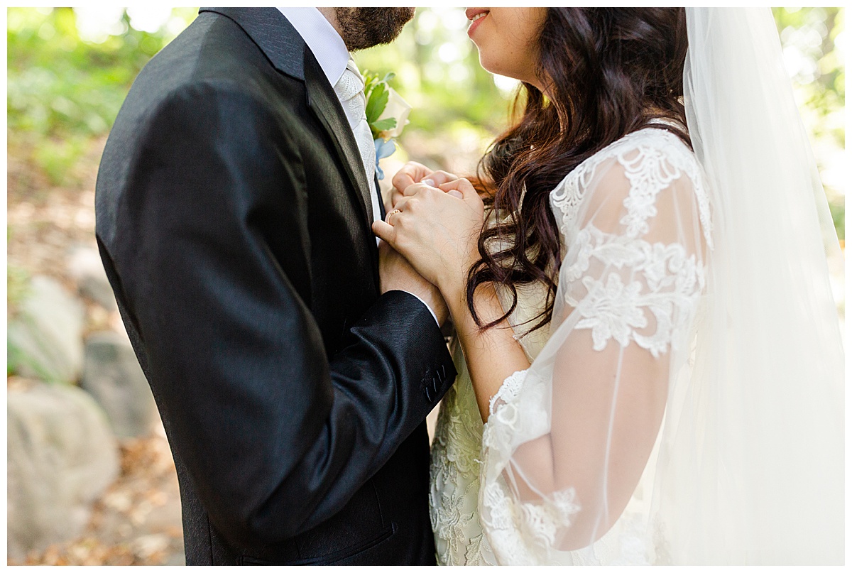 Bride in elegant lace wedding dress holding hands with groom