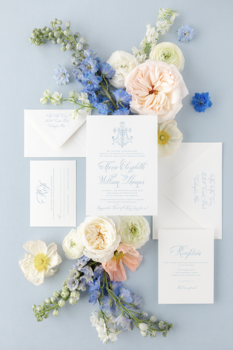 blue themed wedding invitation suite surrounded by florals for a catholic wedding